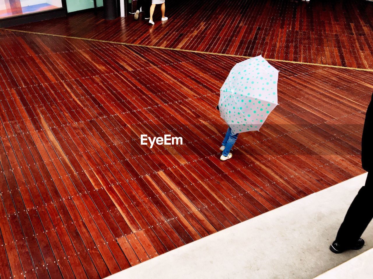 High angle view of child carrying umbrella on boardwalk