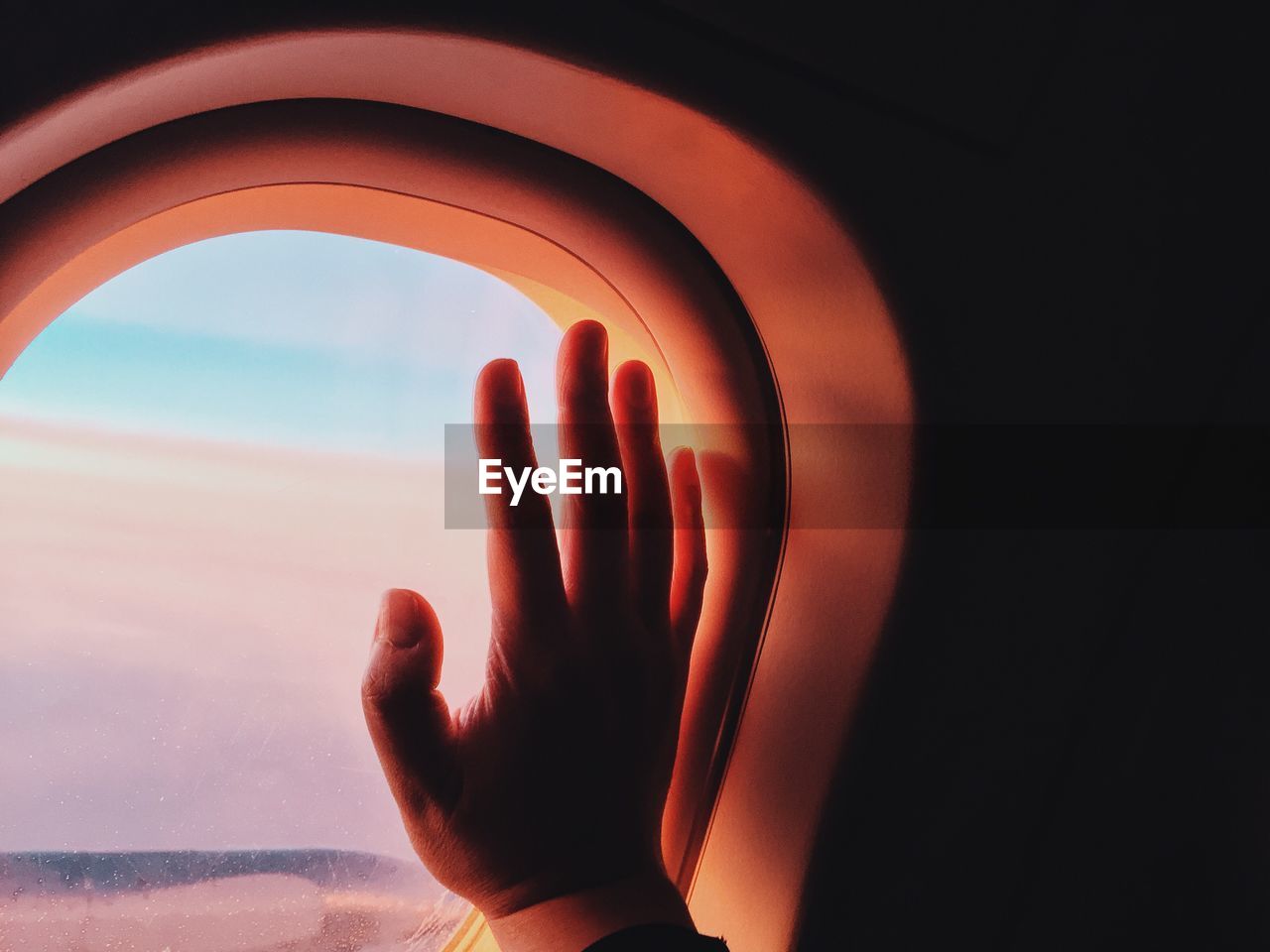 Cropped image of hand on airplane window