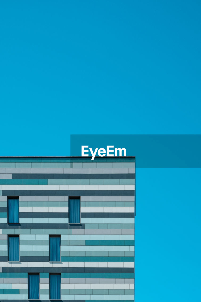 HIGH SECTION OF BUILDING AGAINST BLUE SKY