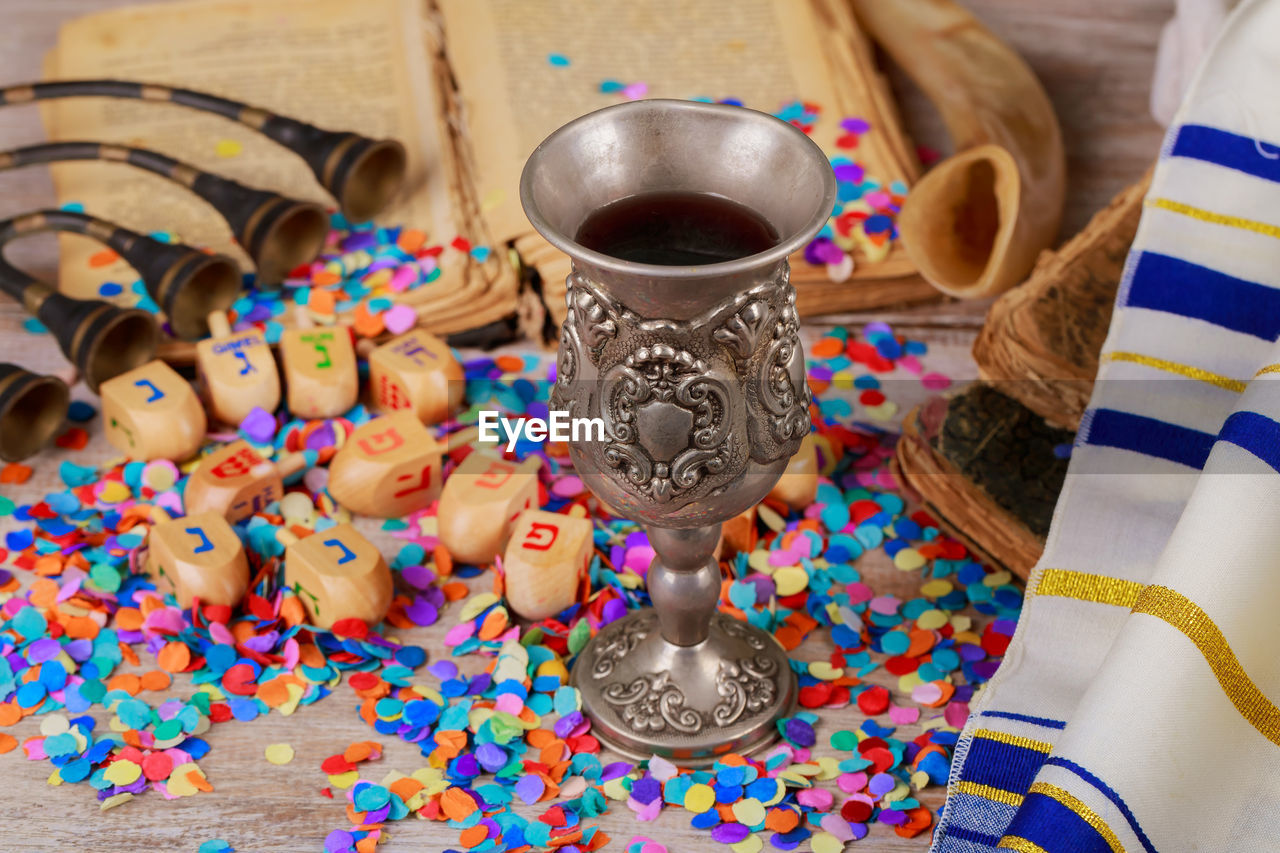 High angle close-up of toy blocks with colorful confetti and drink on wooden table