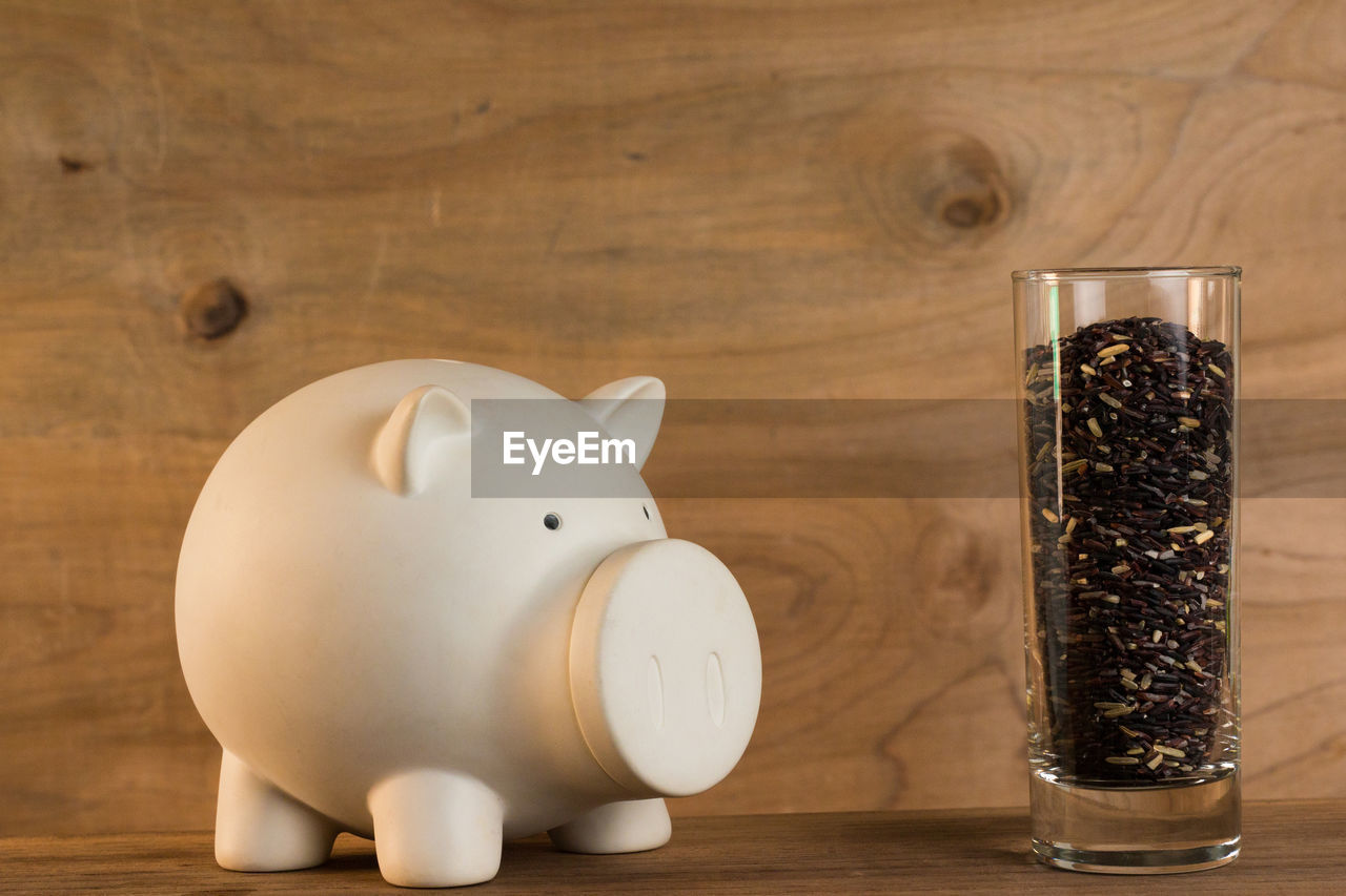 Close-up of piggy bank and food in glass on table