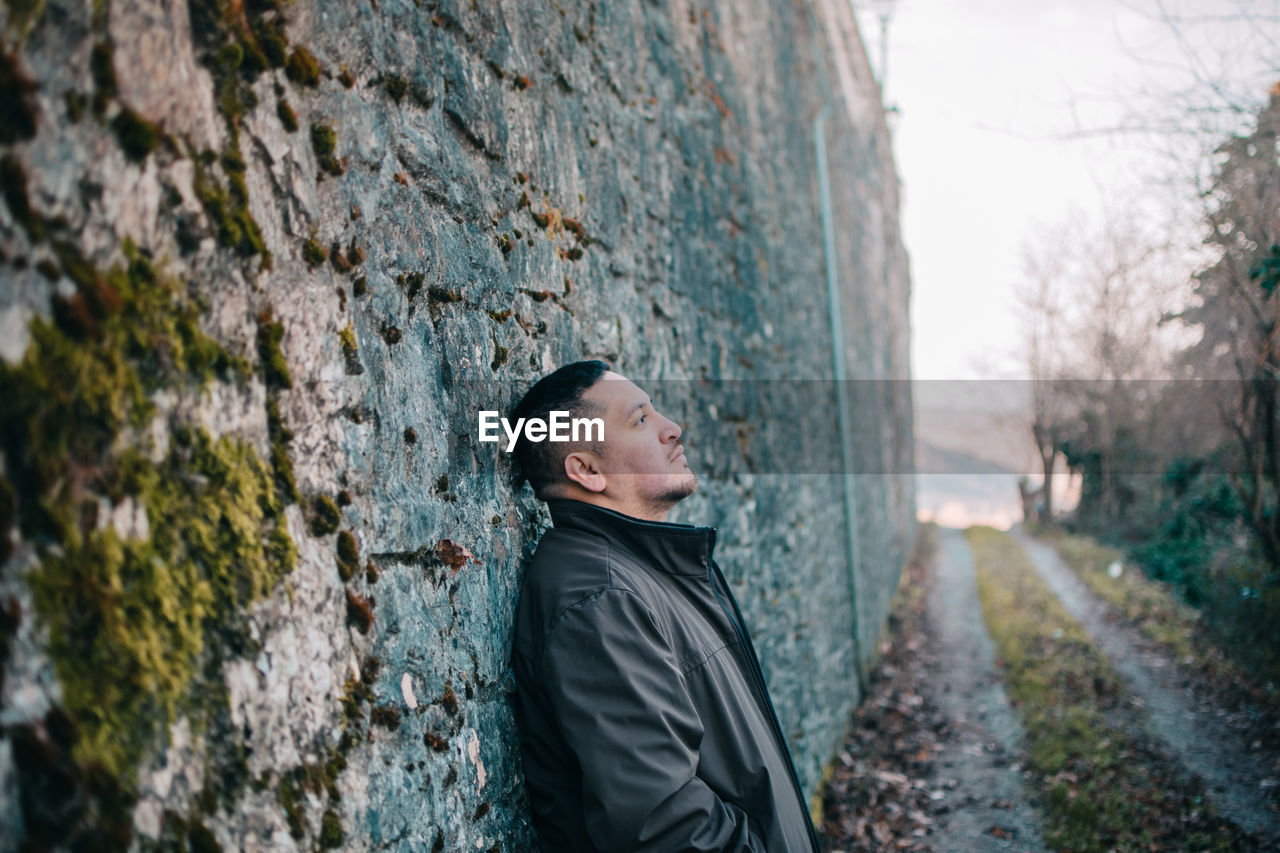 Thoughtful man standing by wall