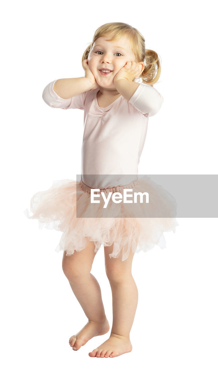 Portrait of cute girl in tutu practicing ballet dance against white background