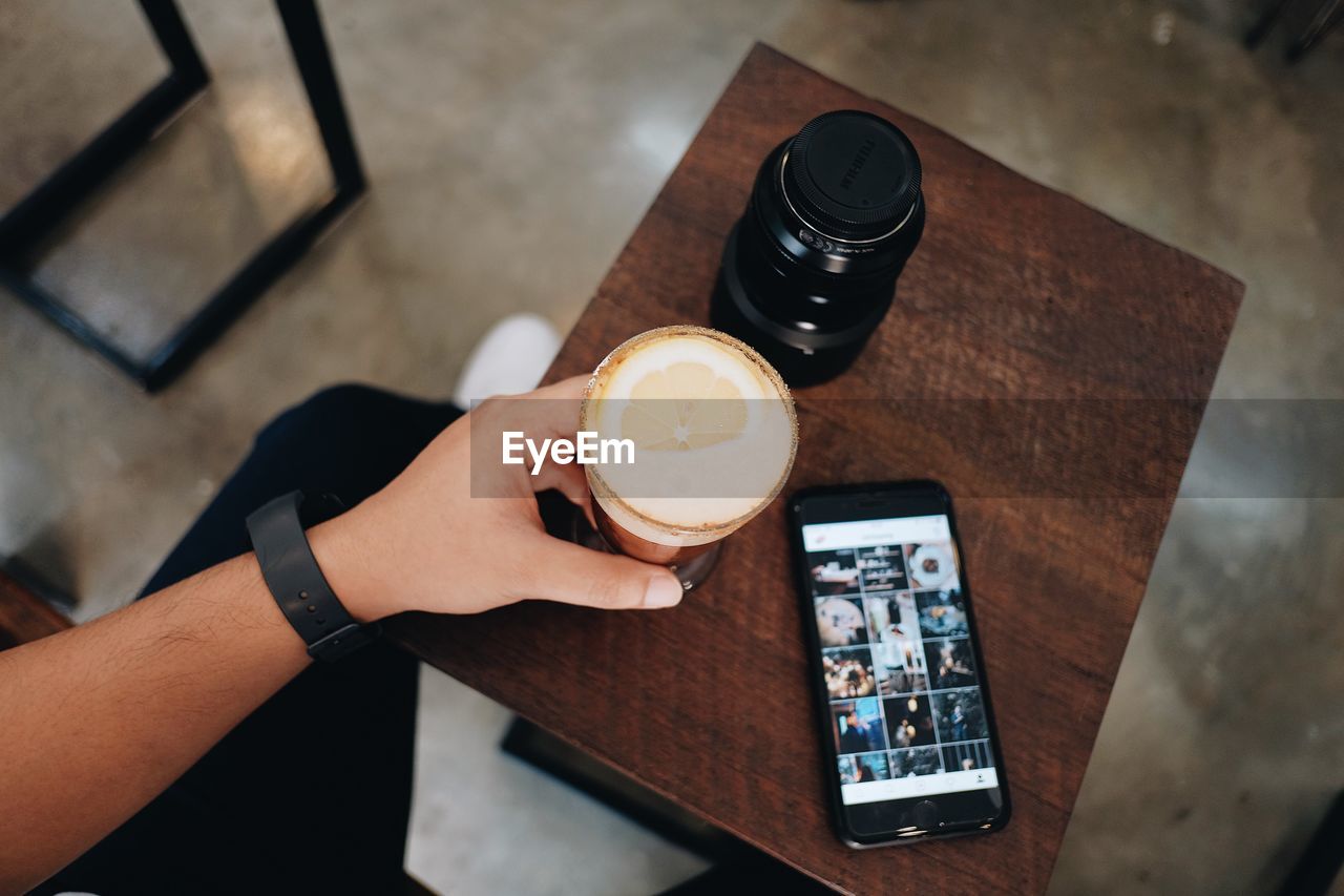 Directly above shot man holding cold coffee at restaurant table