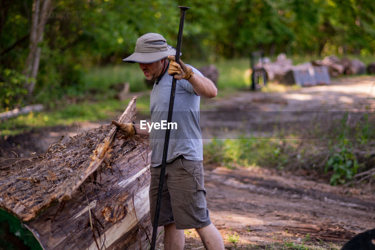 Full length of man working with log in forest