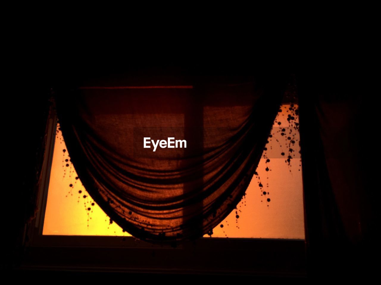 Low angle view of window with curtain during sunset