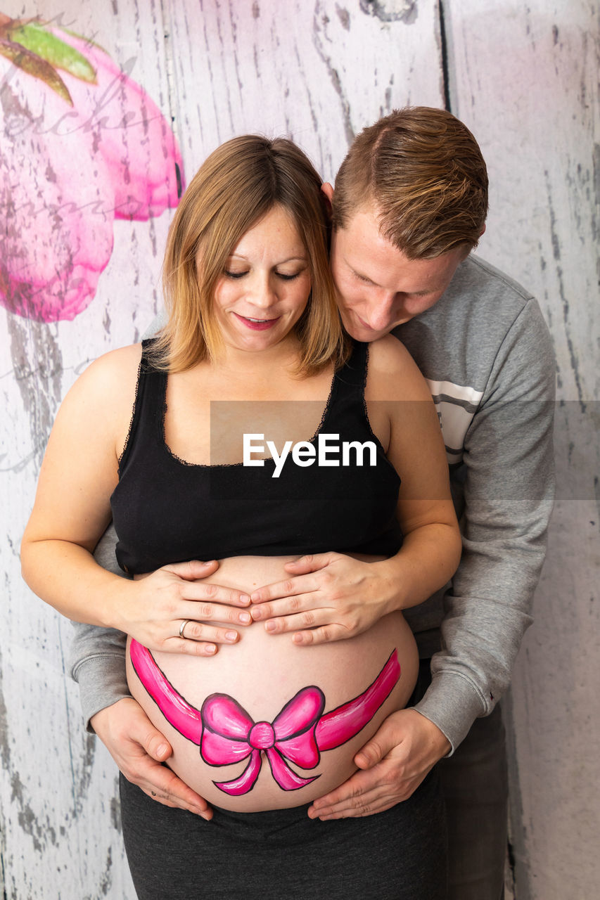 Man standing with pregnant woman against wall