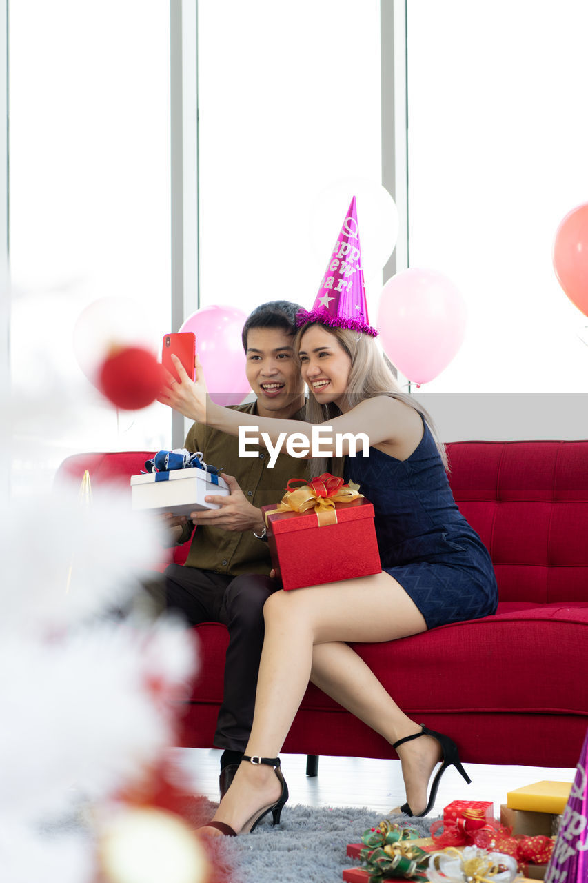 Couple doing selfie while sitting on sofa at home