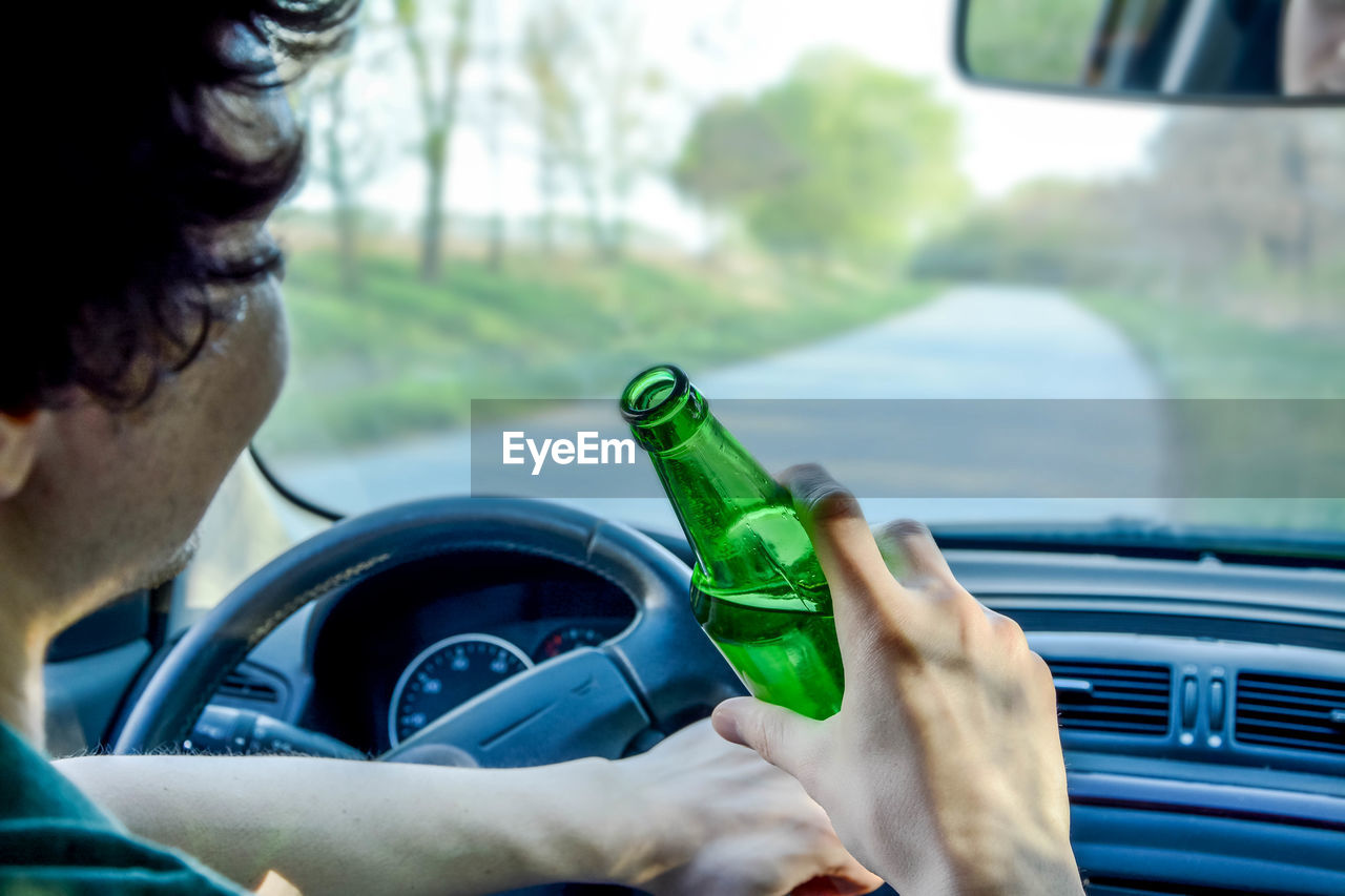 Close-up of man drinking beer while driving car