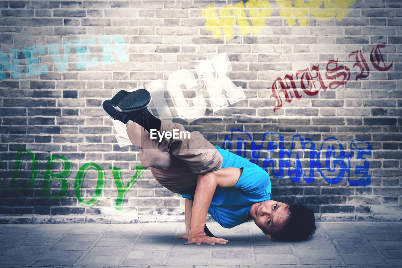 FULL LENGTH OF MAN ON WALL AGAINST BRICK WALLS