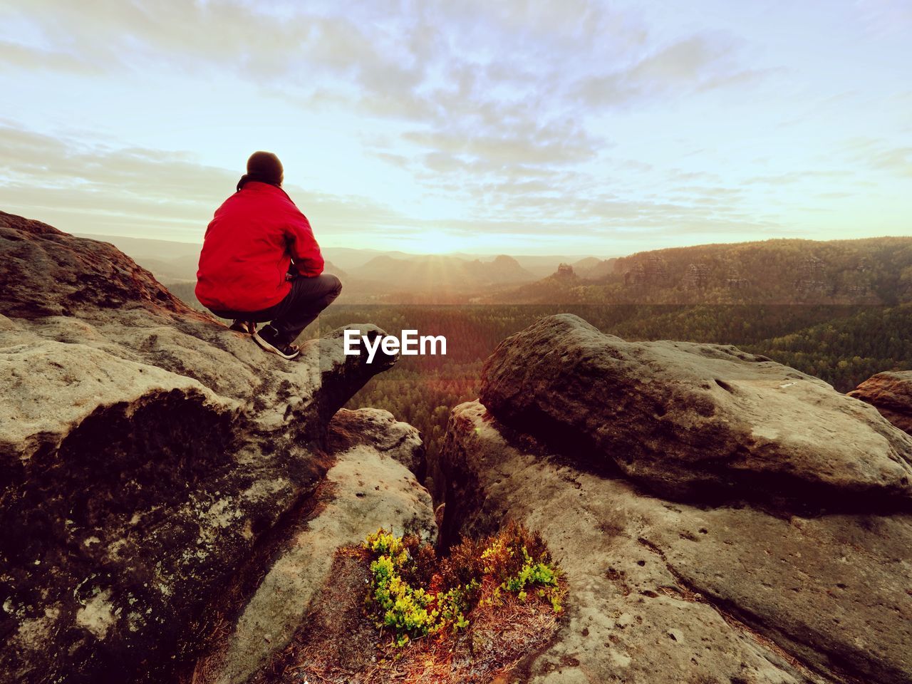 Hiker man take a rest on mountain peak. man lay on summit, bellow autumn valley. bright morning sun