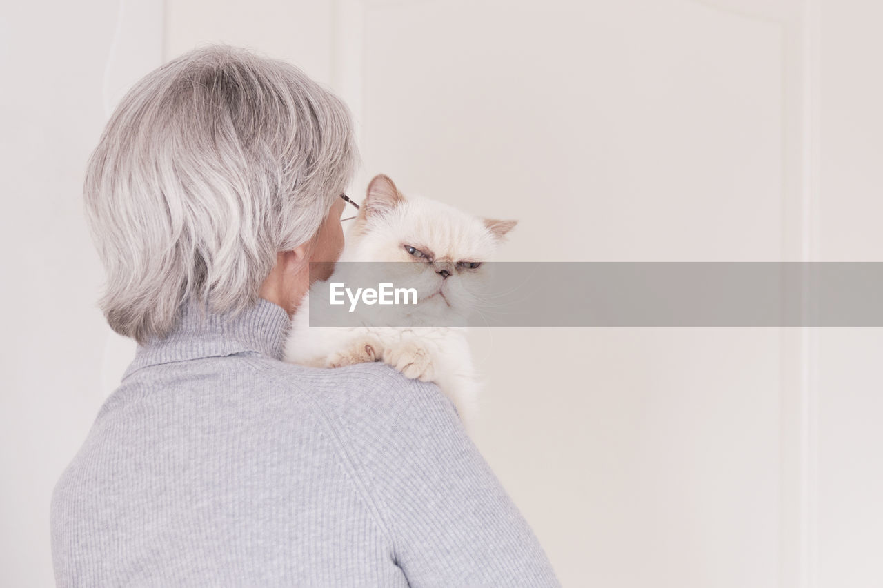 REAR VIEW OF WOMAN WITH DOG AGAINST WHITE BACKGROUND