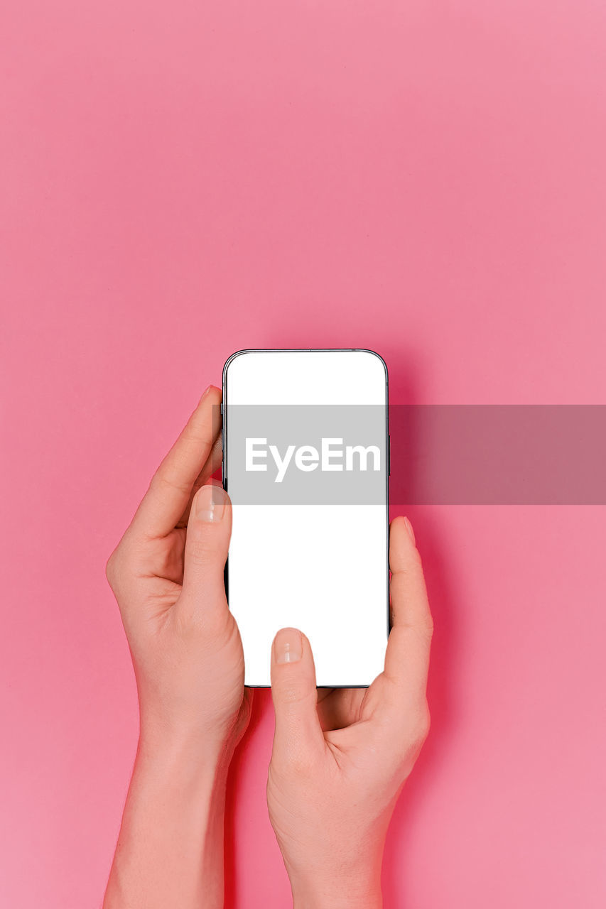 cropped hand of woman using mobile phone against yellow background