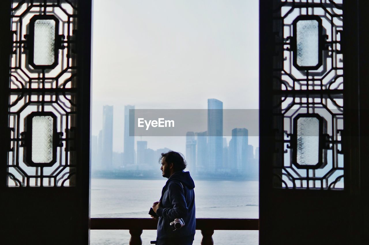 Side view of young man standing by river in balcony