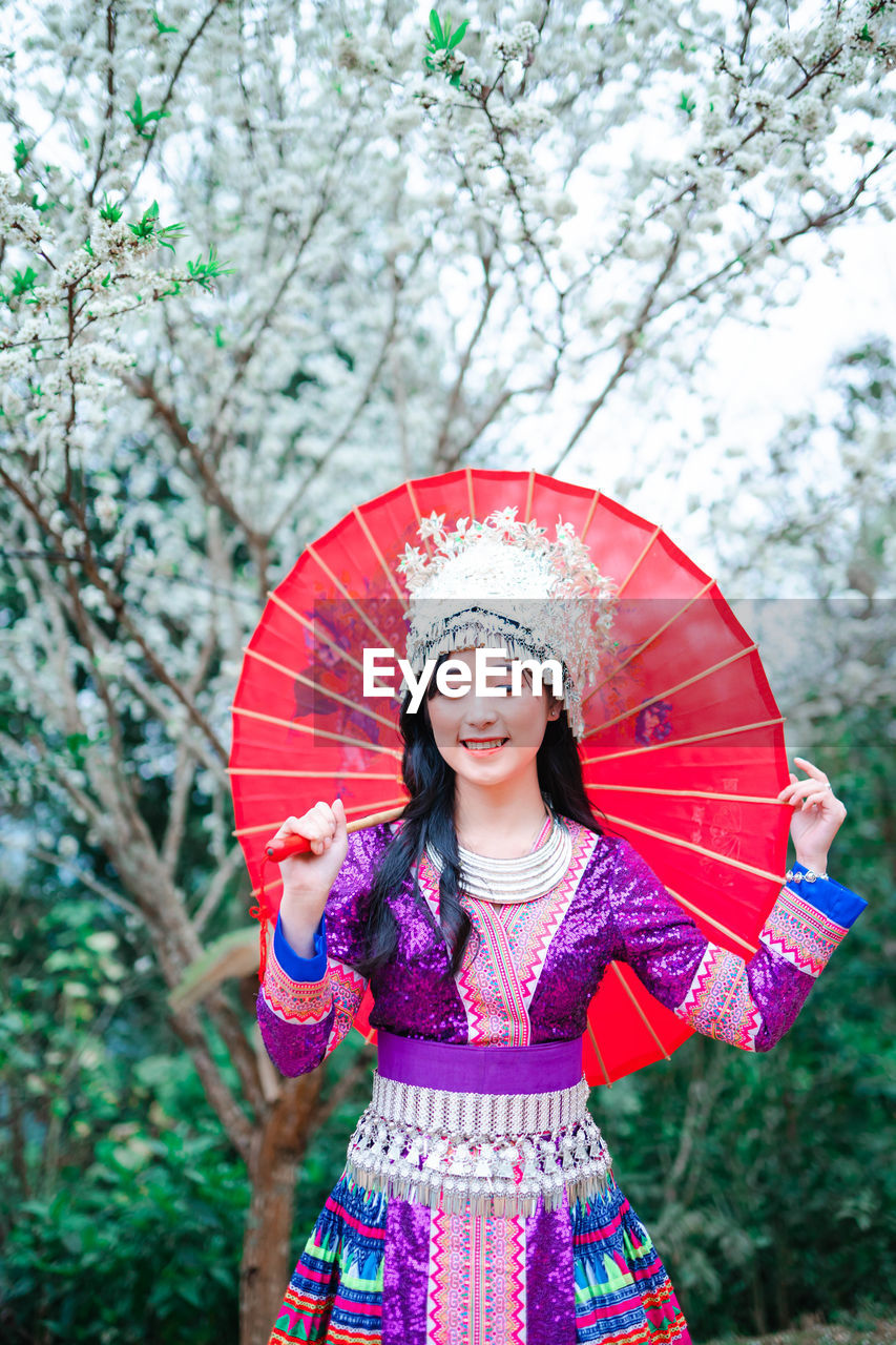 Portrait of a smiling woman standing against trees