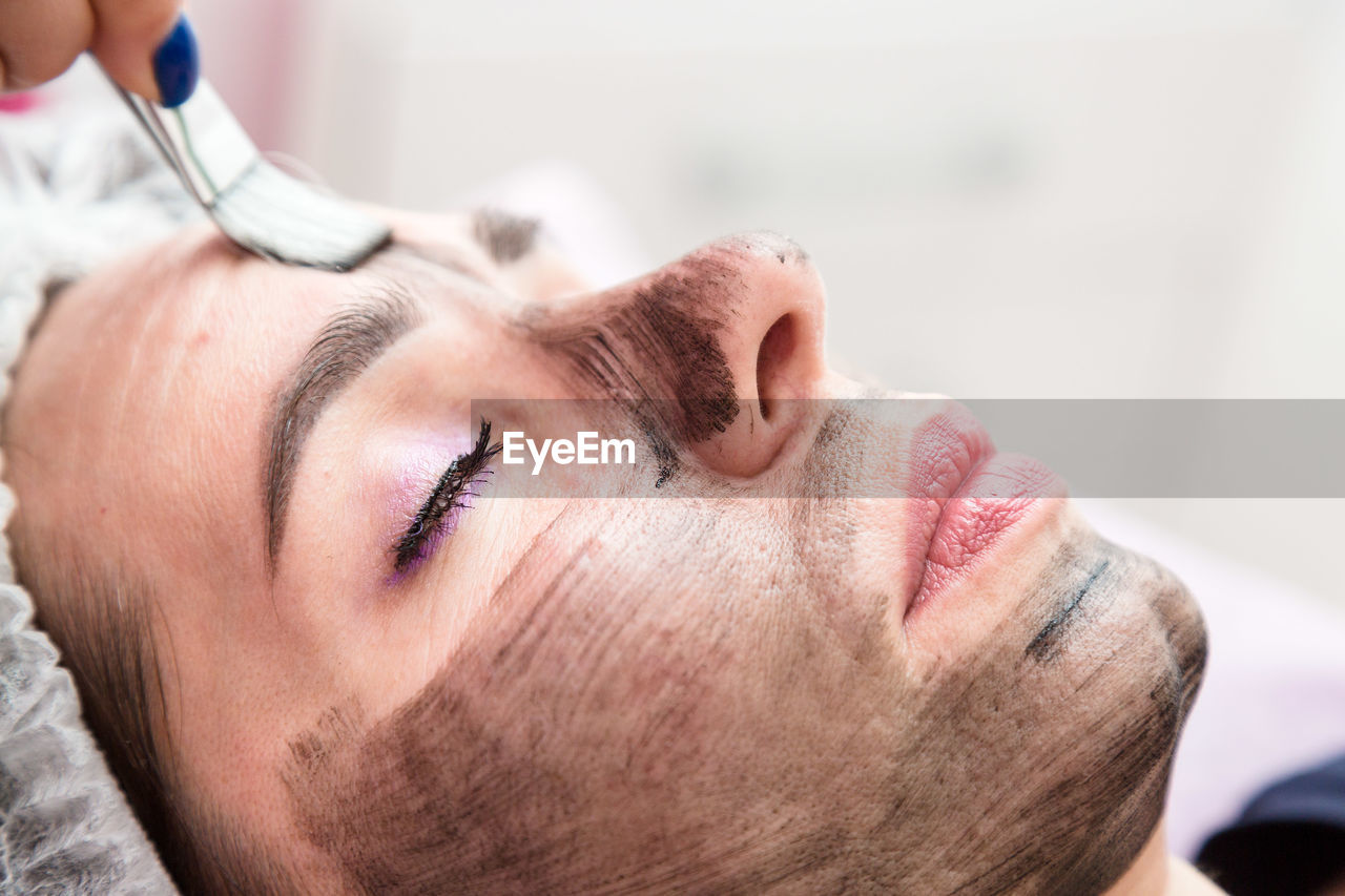 Applying a cream mask for carbon peeling face of an adult woman.