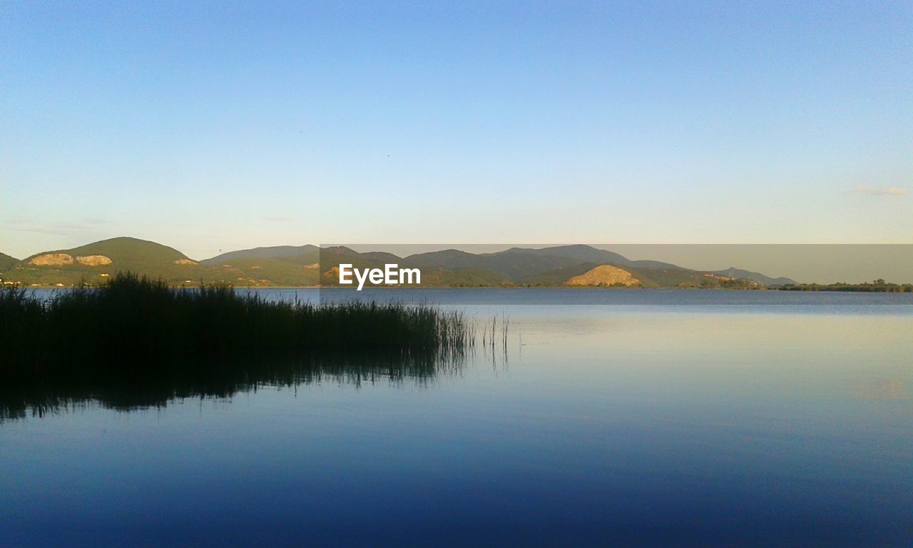 SCENIC VIEW OF LAKE BY MOUNTAINS AGAINST CLEAR BLUE SKY