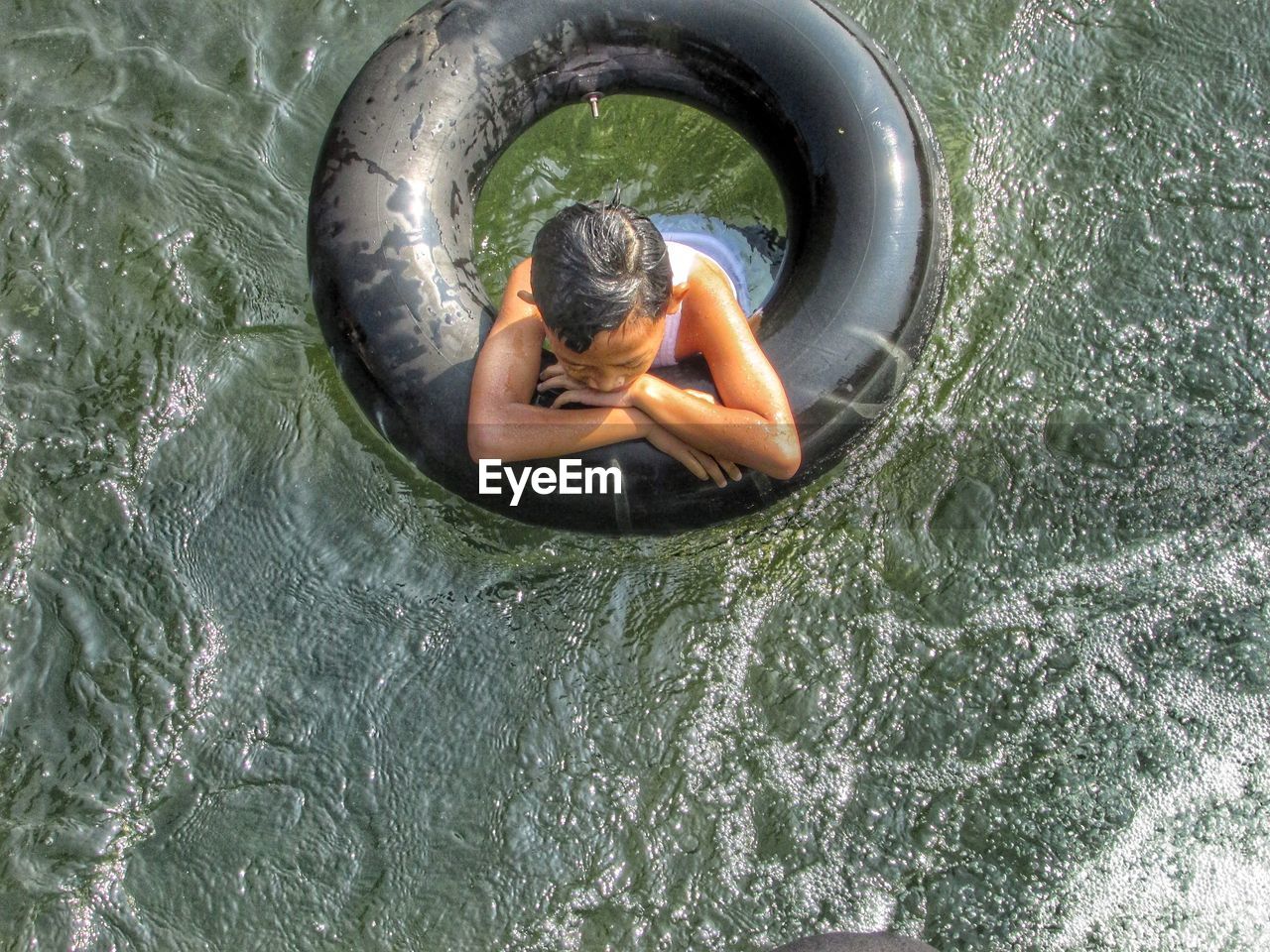 High angle view of boy swimming with inflatable raft in lake