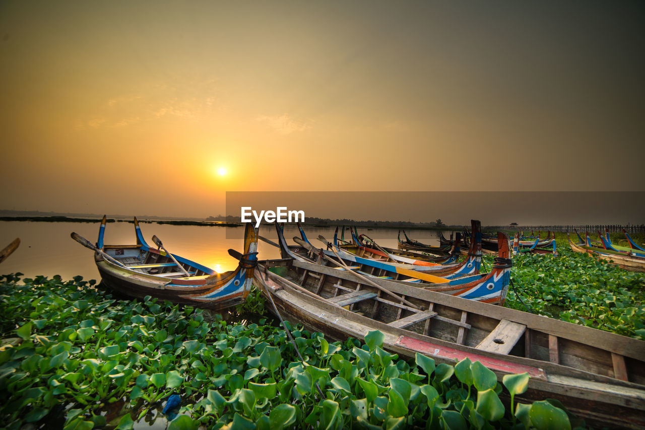 FISHING BOATS MOORED ON SEA AGAINST SKY DURING SUNSET