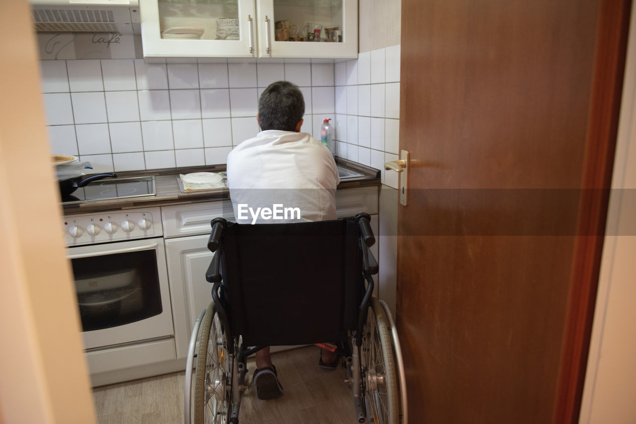 A disabled woman in a wheelchair washes dirty dishes