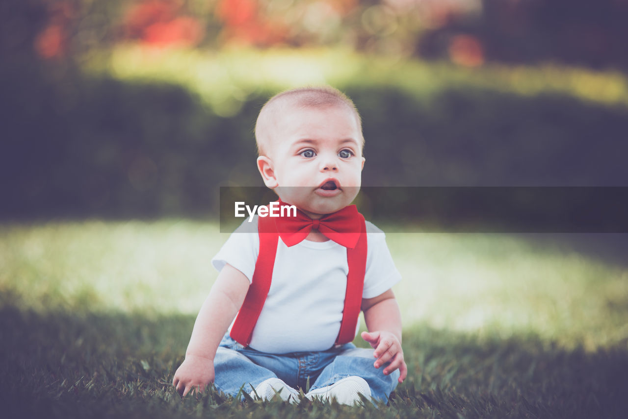 PORTRAIT OF BOY SITTING ON FIELD