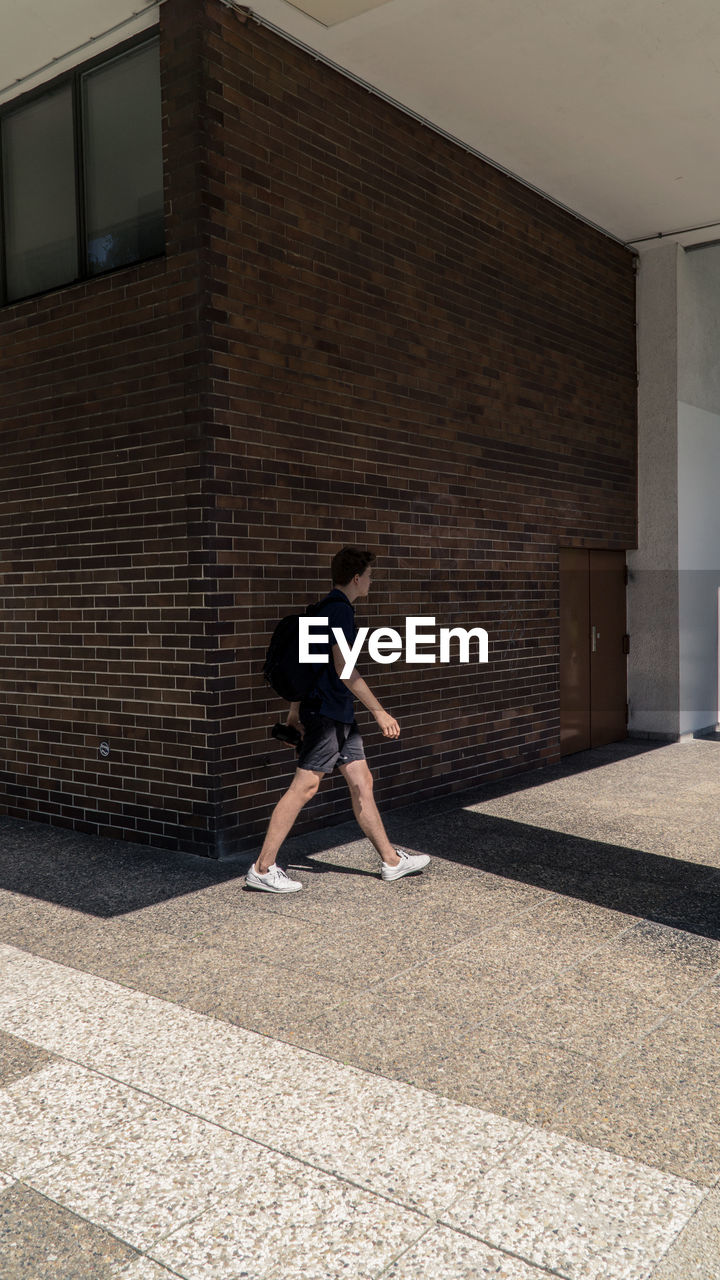 Full length of man walking against built structure