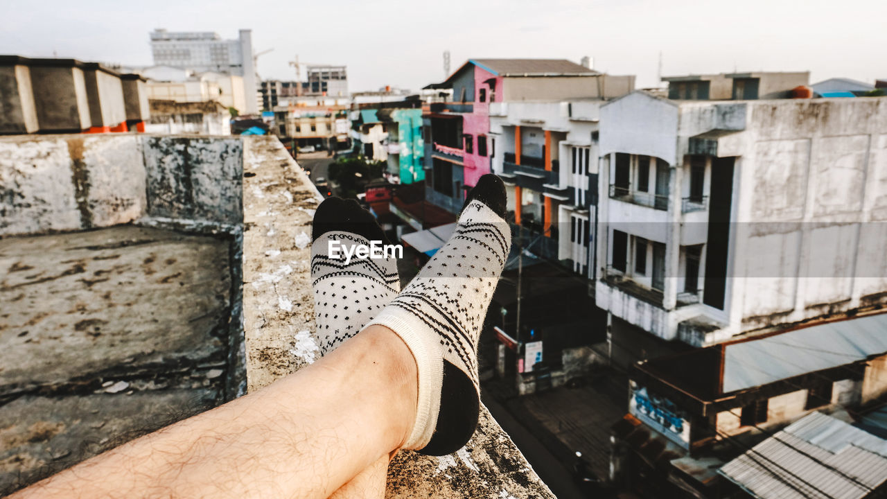 Low section of man relaxing on building terrace in city