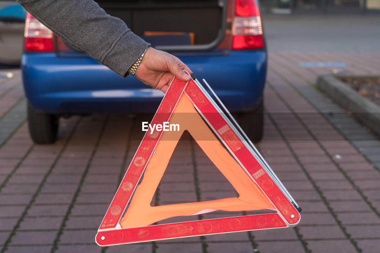 Red triangle warning sign and broken down car in the distance