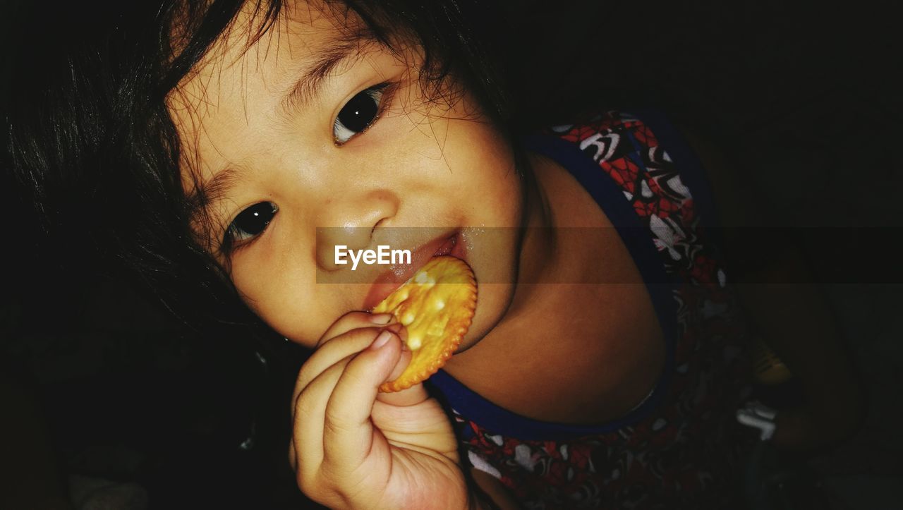 High angle view of little girl eating biscuit