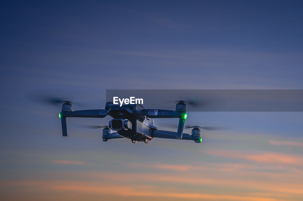 Low angle view of drone flying against sky during sunset