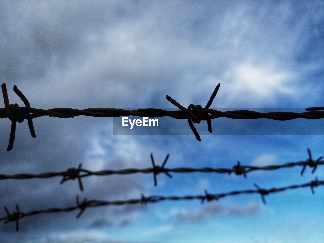 Low angle view of barbed wire against sky