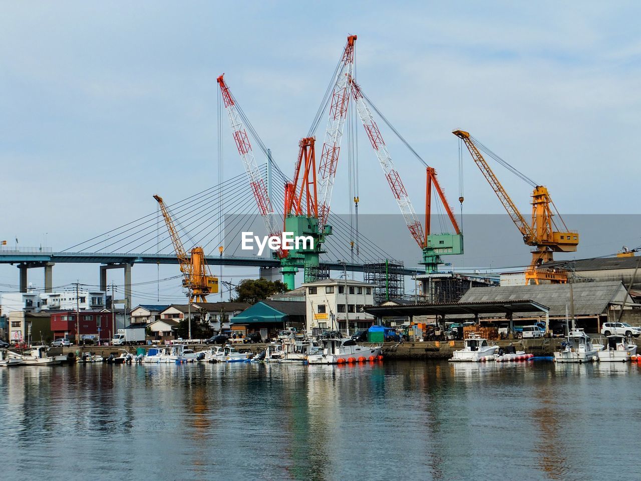 Cranes at commercial dock against sky