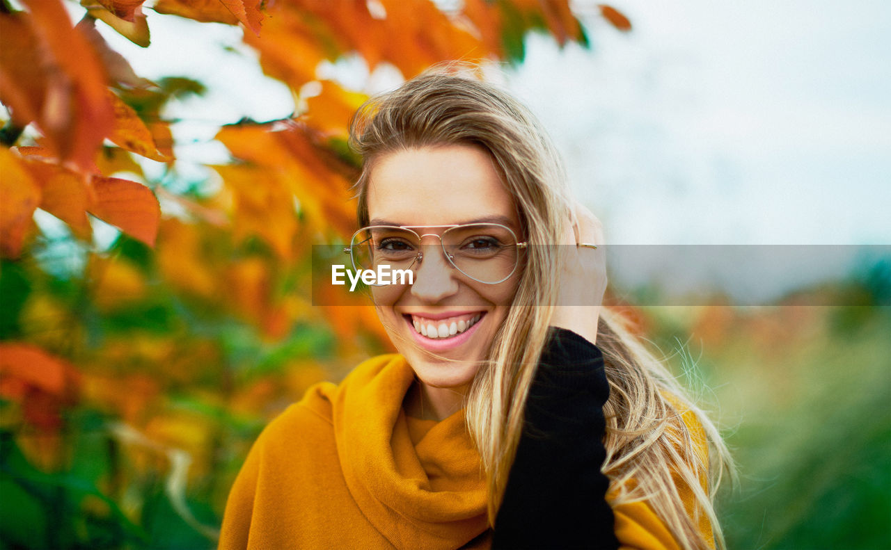 Portrait of smiling woman against tree