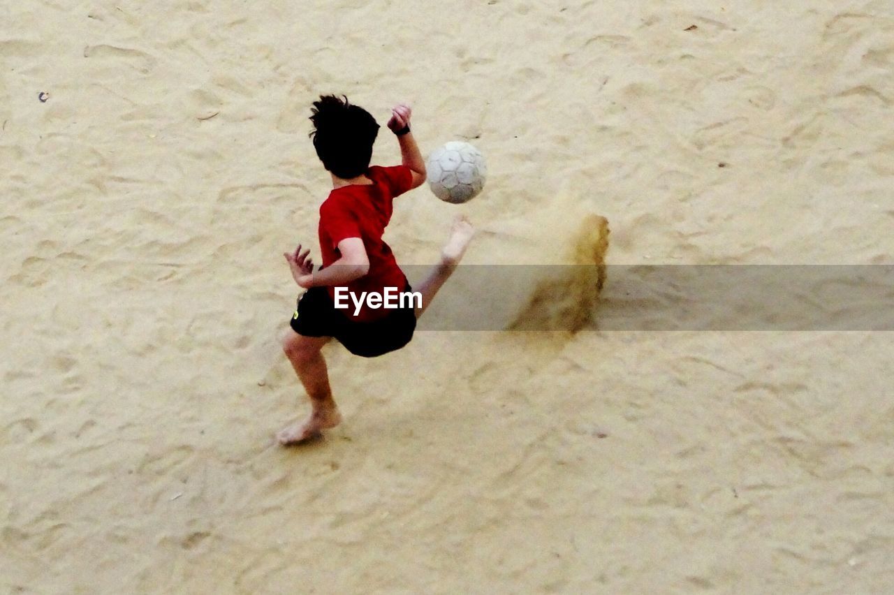 BOY PLAYING WITH BALL ON BEACH