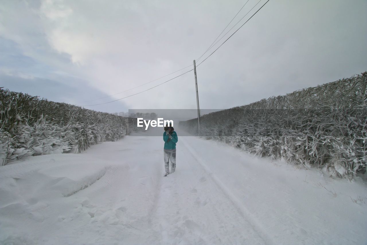 REAR VIEW OF MAN WALKING ON SNOWY MOUNTAIN