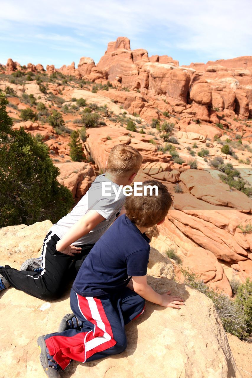 Brothers sitting on rock at desert
