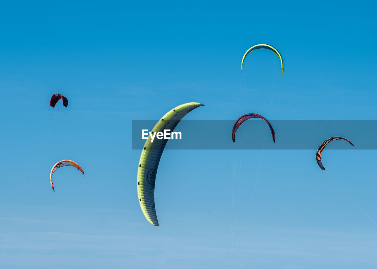 low angle view of person paragliding against blue sky