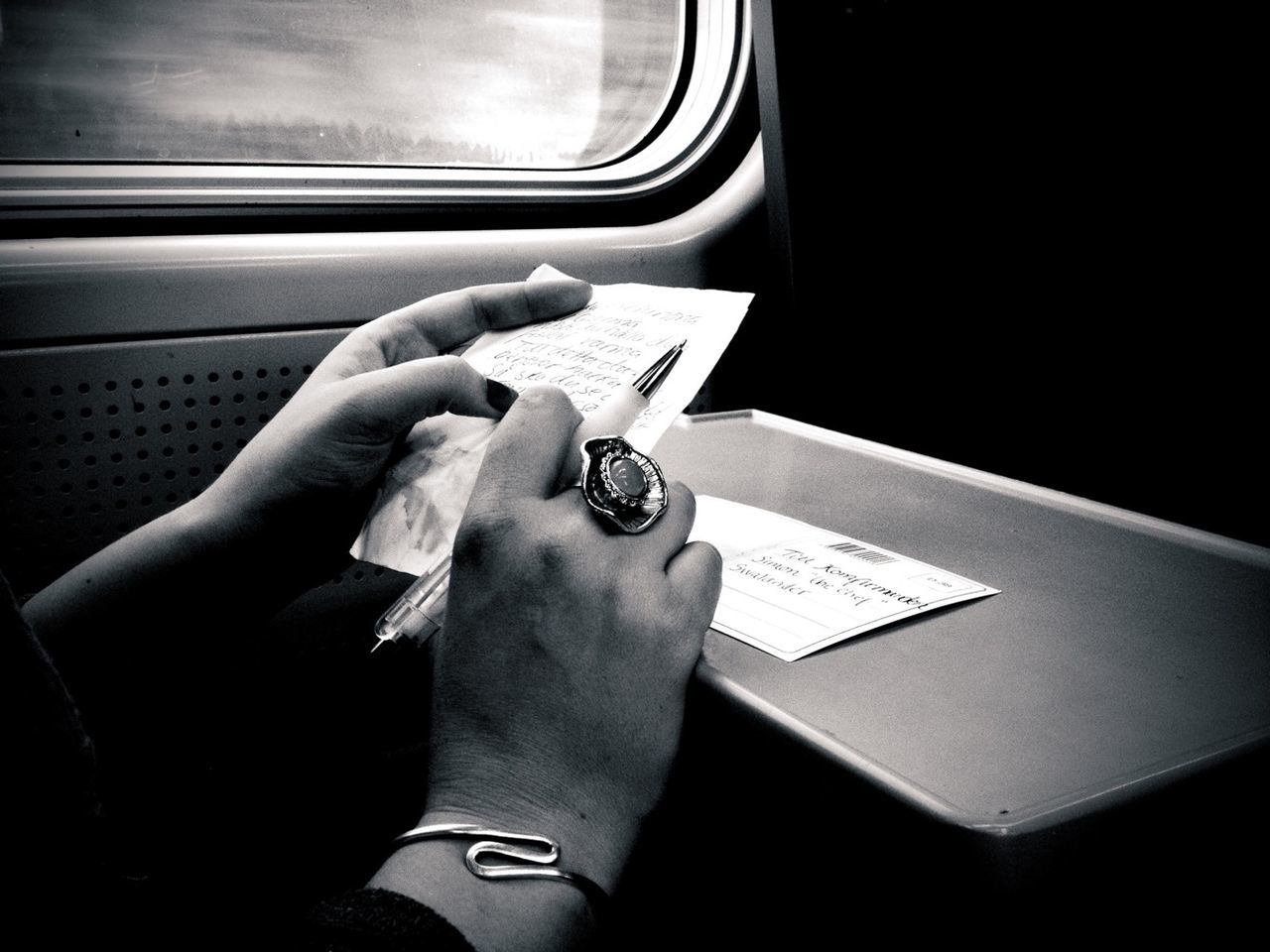 Hands of woman reading postcard in train