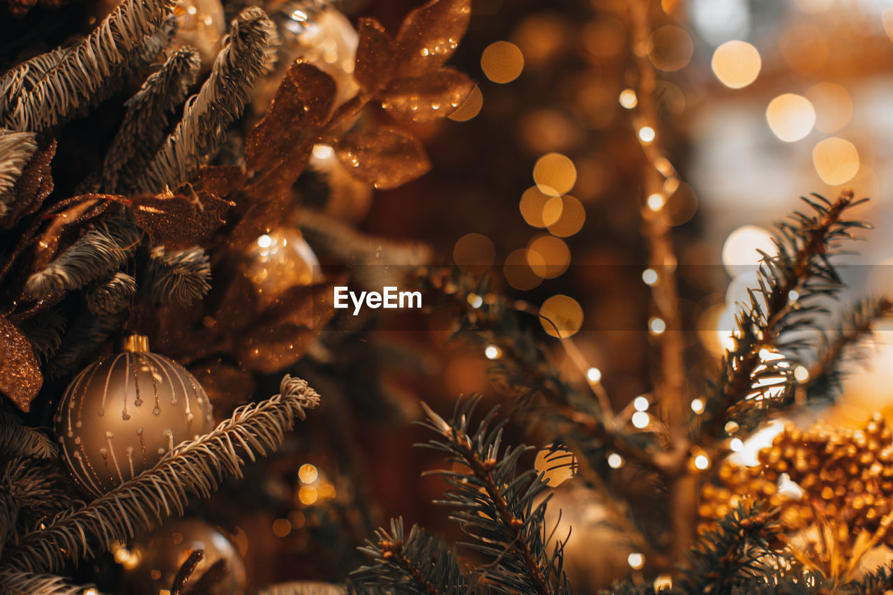 Winter holiday composition. golden christmas ball and shiny garland hanging on the christmas tree.