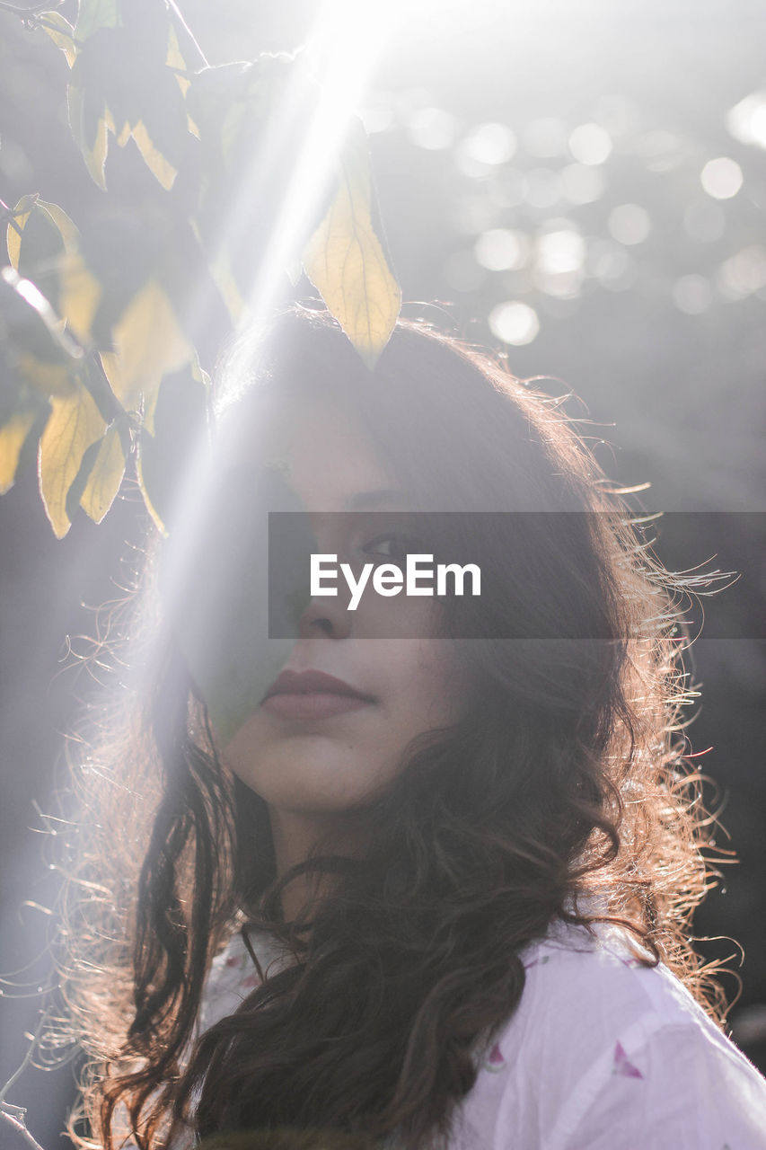 Portrait of beautiful woman by leaves on tree in forest
