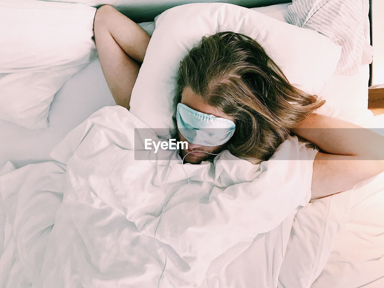 High angle view of man wearing sleep mask on bed at home