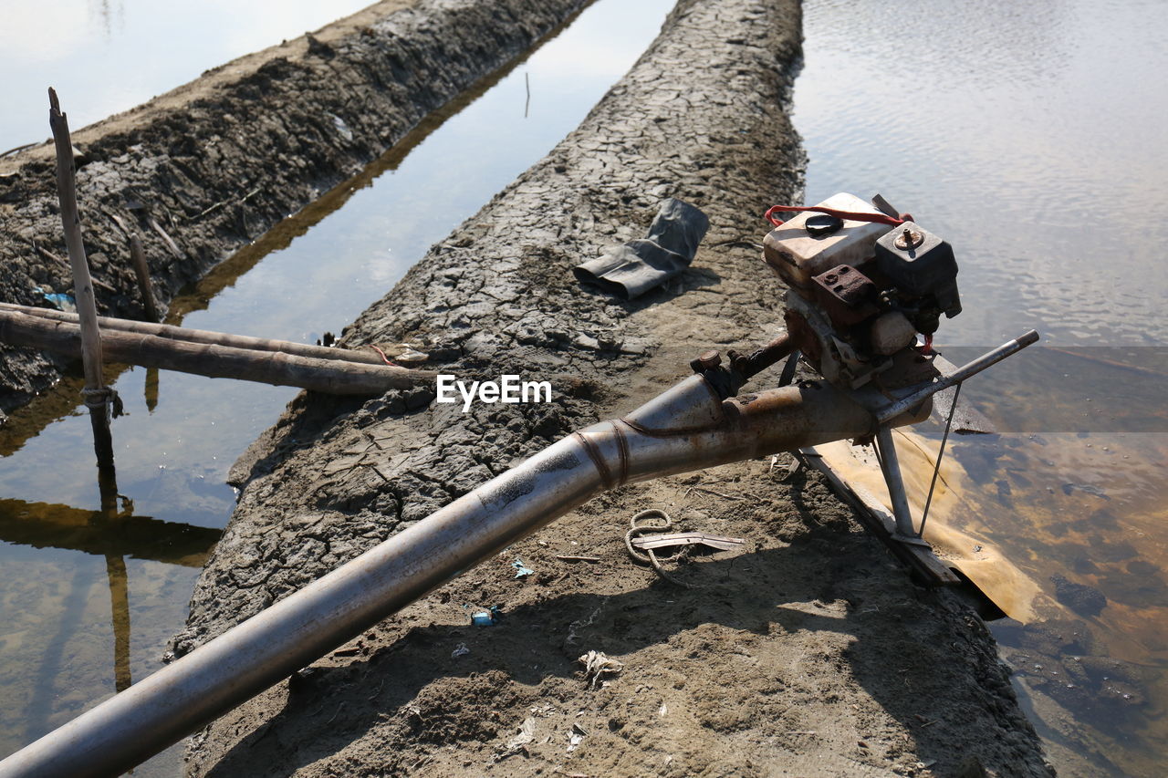 HIGH ANGLE VIEW OF PIPE ON TREE BY WATER