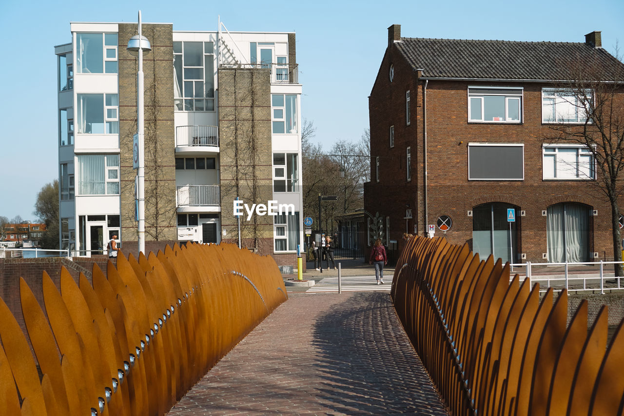 FOOTPATH AMIDST BUILDINGS AGAINST SKY