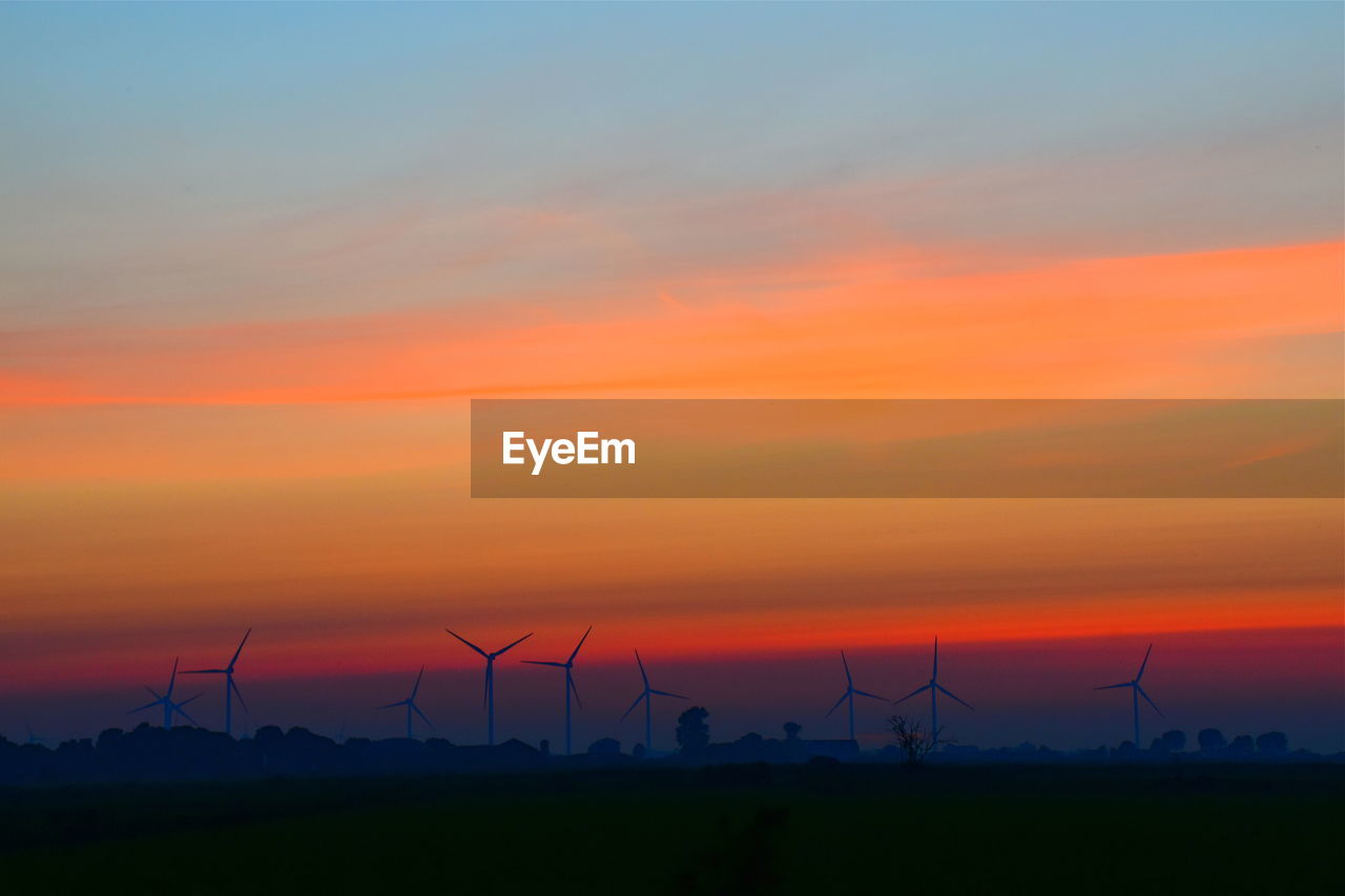 SILHOUETTE OF WIND TURBINES AT SUNSET