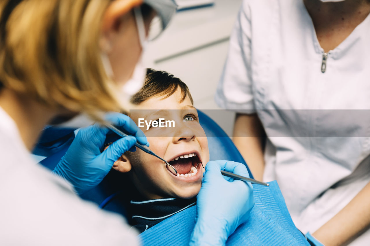 Dentist operating boy in medical clinic