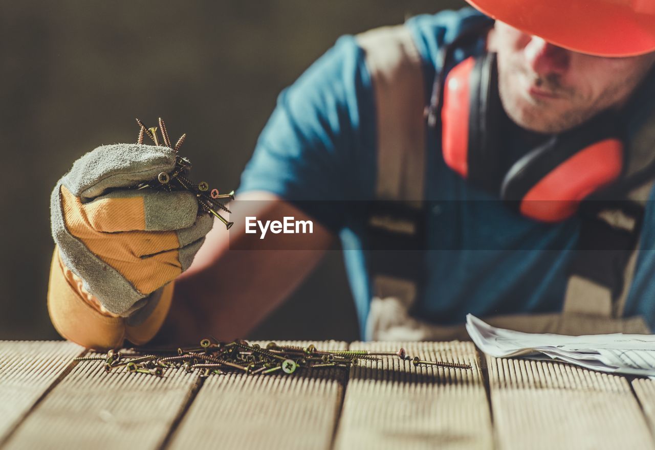 Close-up of man holding nails at table