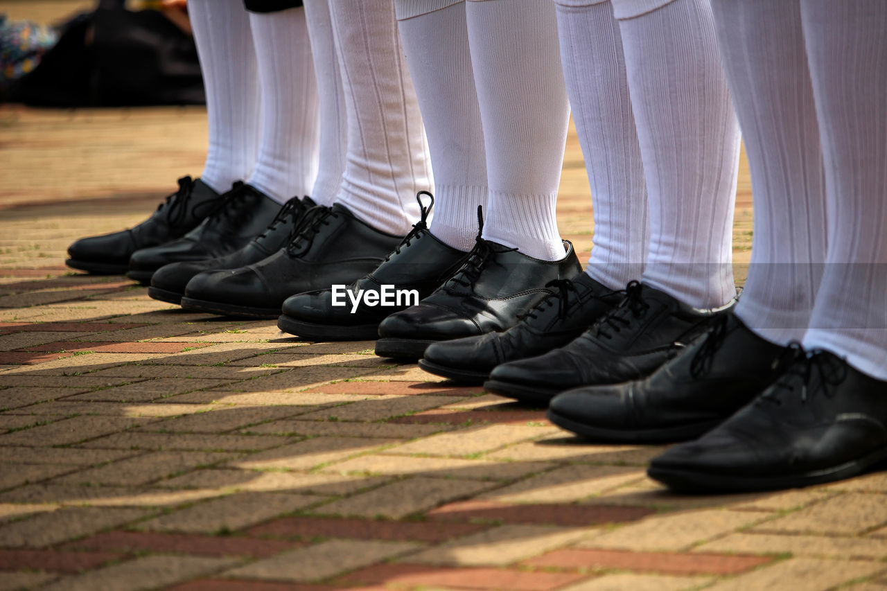 Low section of people wearing shoes standing on floor