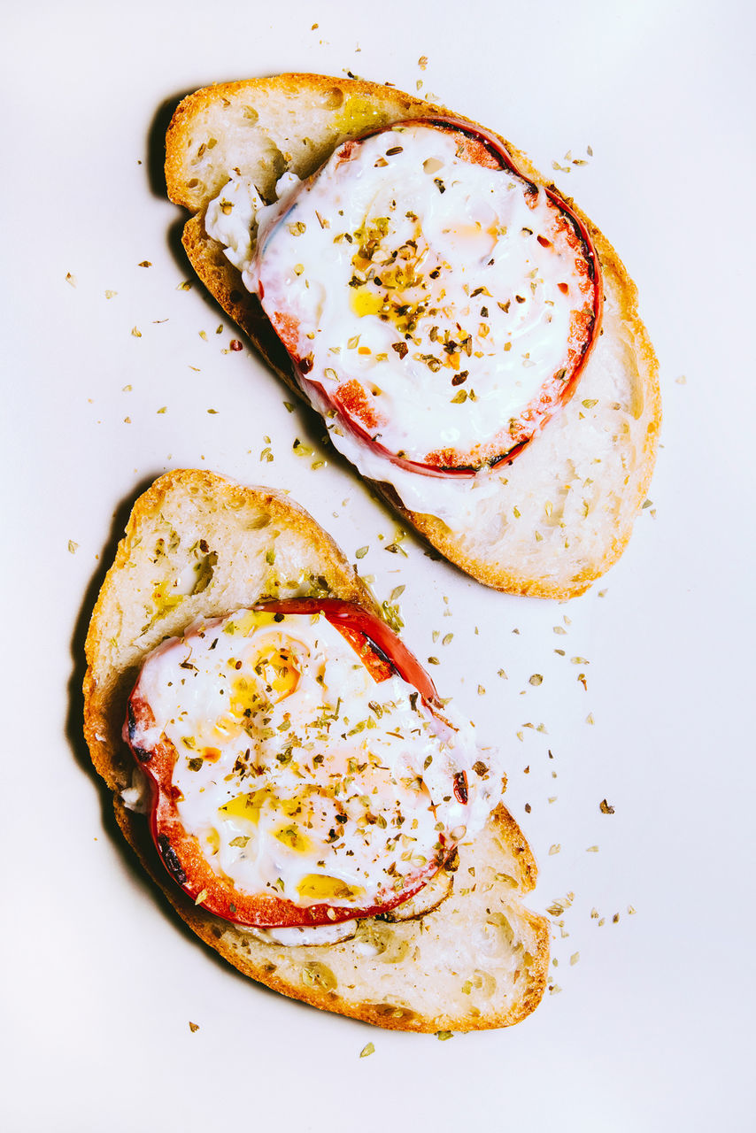 Directly above view of fresh bread with tomato and egg against white background