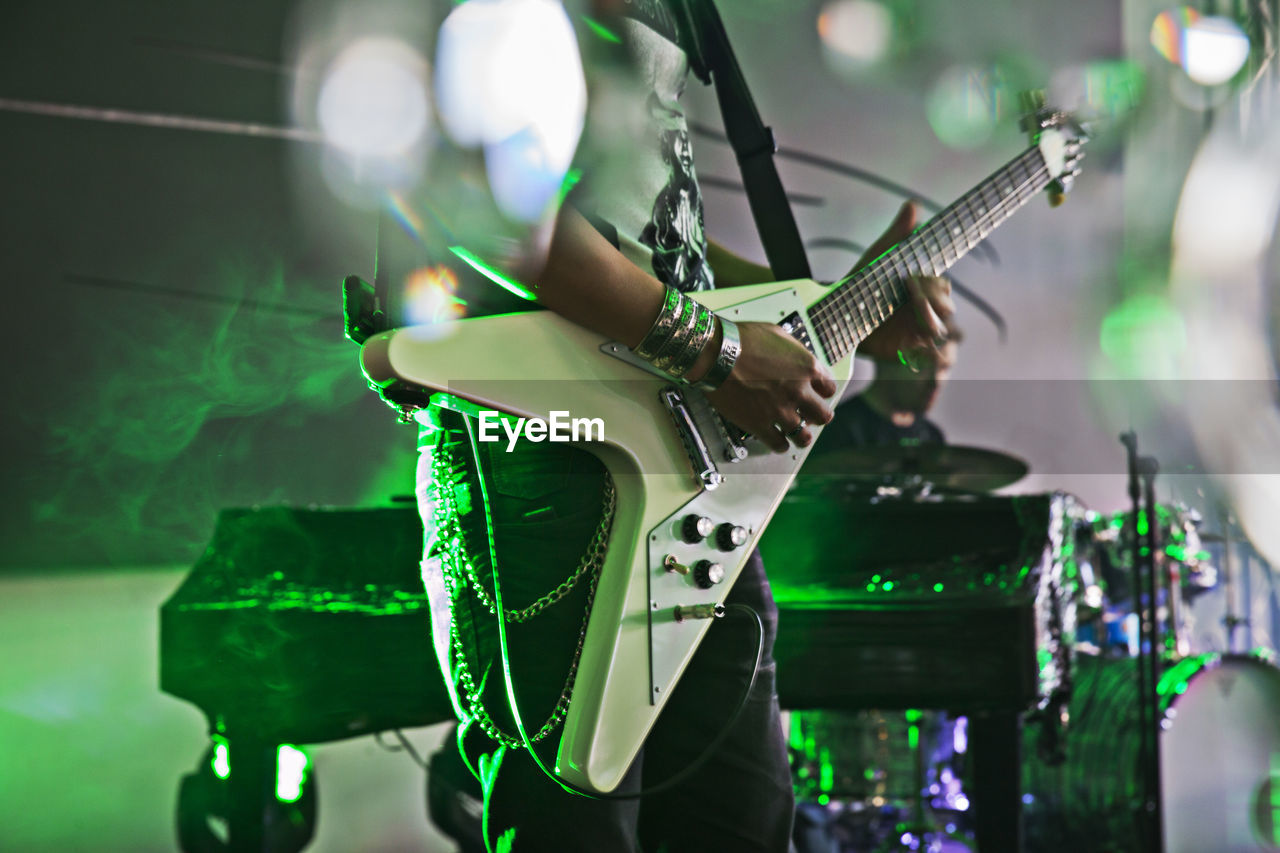 Midsection of musician playing guitar at concert