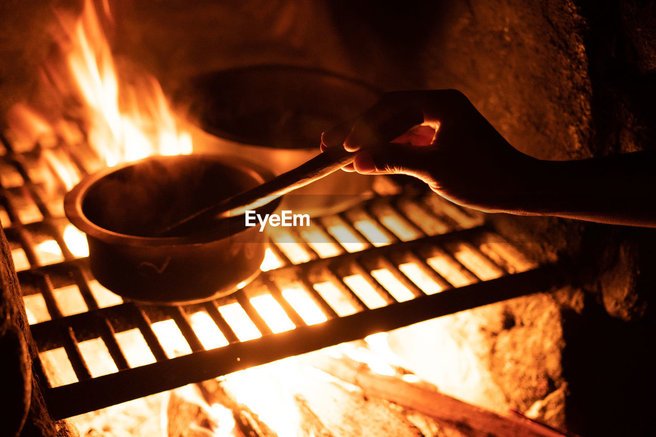 Close-up of food being prepared by fire in hiking hut. 